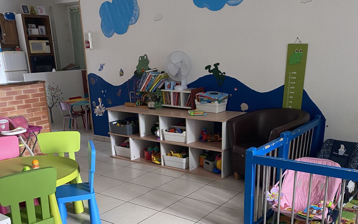 Image MAM 3 agrandie — Espace lecture et jeux d'éveil de la MAM avec bibliothèque et bacs à jouets